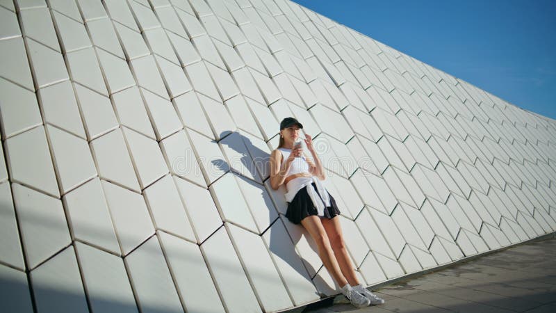 Sportswear femme boire une boisson debout mur urbain géométrique se sentir détendu image stock