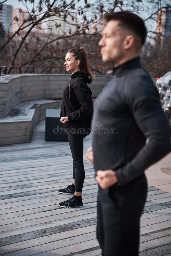 Pleased female keeping firm position on terrace floor with fists near her waist with men beside her doing the same. Qigong class stock images, royalty-free photos and pictures