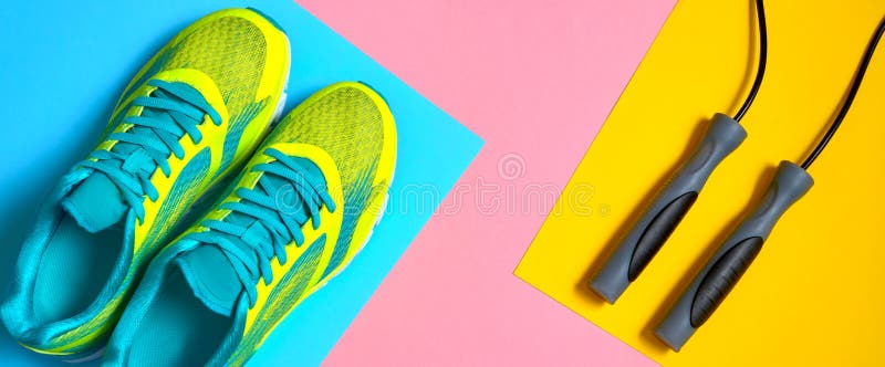 Sportutrustning med springskor och överhopprep på rosa, blå och gul pastellfärgad bakgrund, kopieringsutrymme för text Top besk?d arkivbilder Sportutrustning med springskor och överhopprep på rosa, blå och gul pastellfärgad bakgrund, kopieringsutrymme för text Top besk?d arkivbilder