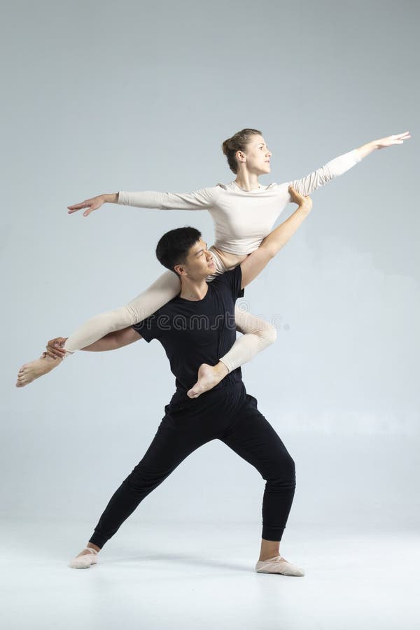 Sporty Asian Man and Caucasian Woman utförde som lastpallsdansare på grå i Studio under föreställningar som klassisk dansning och royaltyfri foto