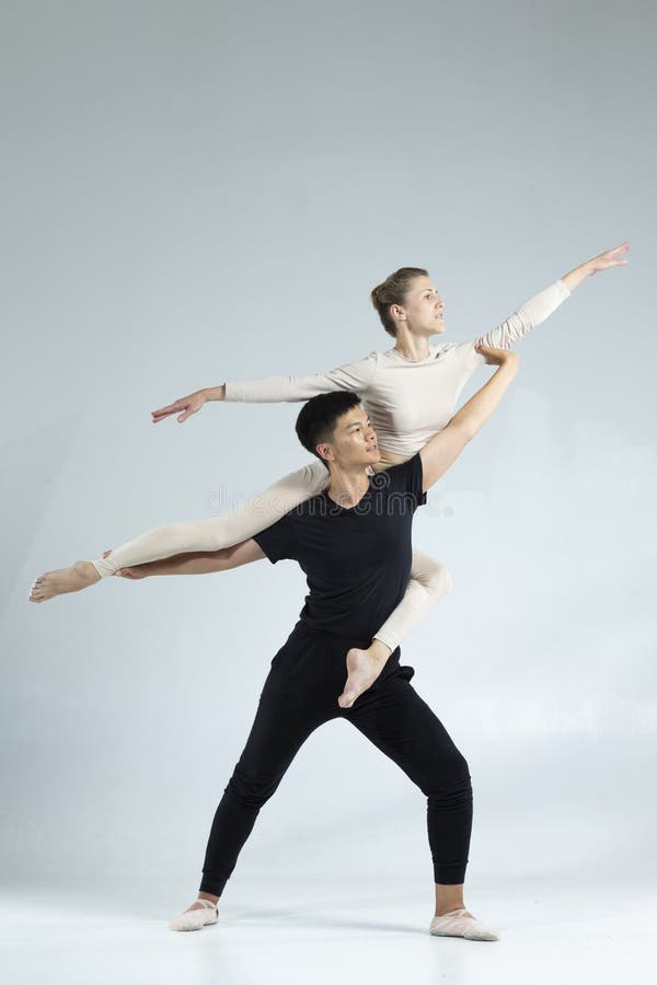 Sporty Asian Man och Caucasian Woman, som vid understödjande studier utför ballongdansare på grå i Studio fotografering för bildbyråer