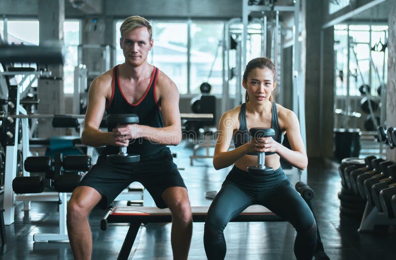 Sporty couple man and woman exercise with dumbbells or does the exercises at gym royalty free stock image Sporty couple man and woman exercise with dumbbells or does the exercises at gym royalty free stock image