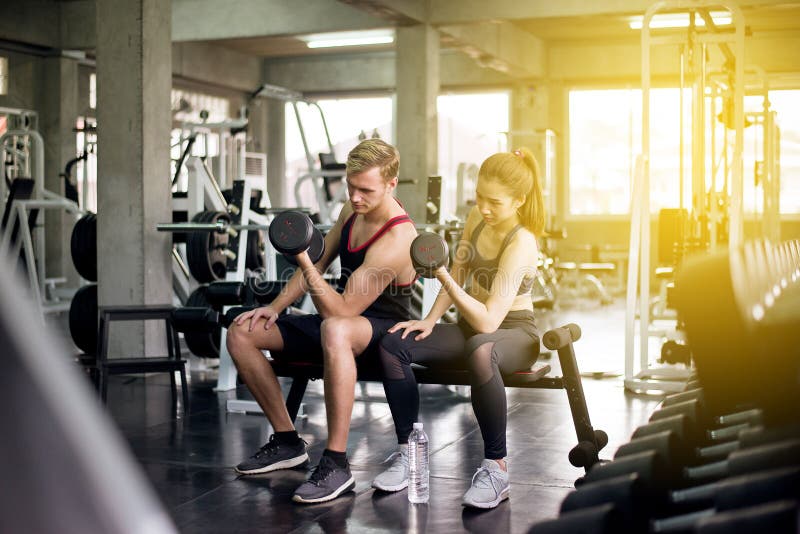 Sporty man and woman exercise lifting dumbbells together,Couple sport people in sportswear does the exercises at gym stock image Sporty man and woman exercise lifting dumbbells together,Couple sport people in sportswear does the exercises at gym stock image
