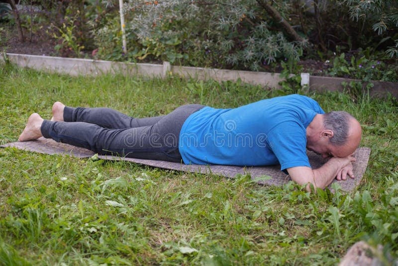 Sporty senior man resting after yoga, fitness, pilates practice lying on mat on grass stock image Sporty senior man resting after yoga, fitness, pilates practice lying on mat on grass stock image