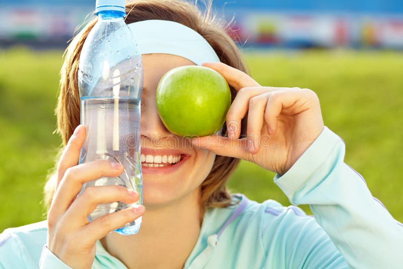 Sporty smiling woman with a water bottle and green apple royalty free stock photo Sporty smiling woman with a water bottle and green apple royalty free stock photo