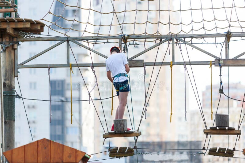 Sporty, young, cute boy in blue t shirt spends his time in adventure rope park in helmet and safe equipment in the park stock photography Sporty, young, cute boy in blue t shirt spends his time in adventure rope park in helmet and safe equipment in the park stock photography