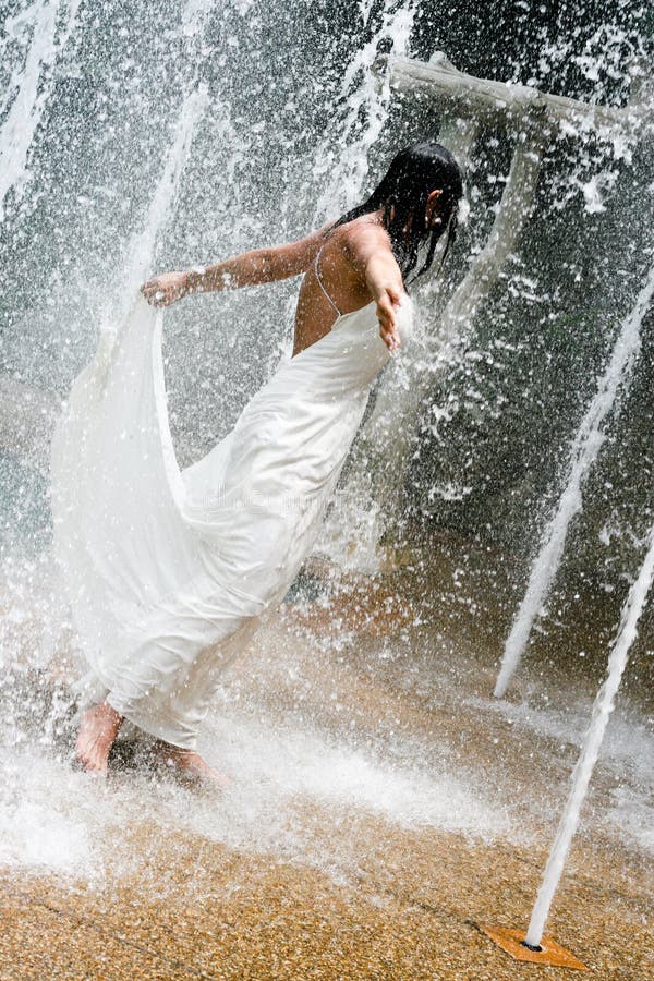 Beautiful young bride playing in a waterfall on her wedding day. Beautiful young bride playing in a waterfall on her wedding day.