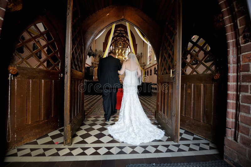 Sposa che cammina giù la navata laterale con il padre fotografia stock Sposa che cammina giù la navata laterale con il padre fotografia stock