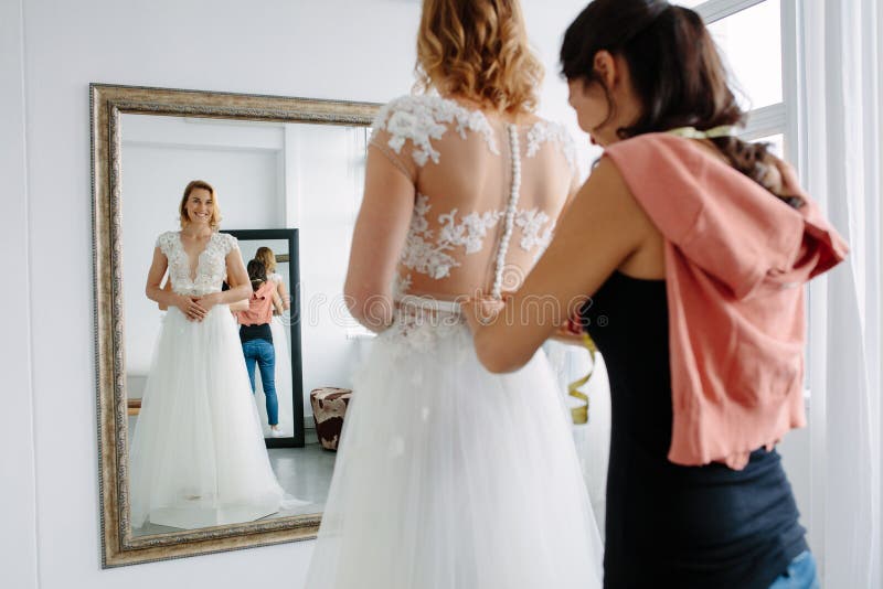 Sposa che prova sul vestito da sposa in un negozio immagini stock libere da diritti Sposa che prova sul vestito da sposa in un negozio immagini stock libere da diritti