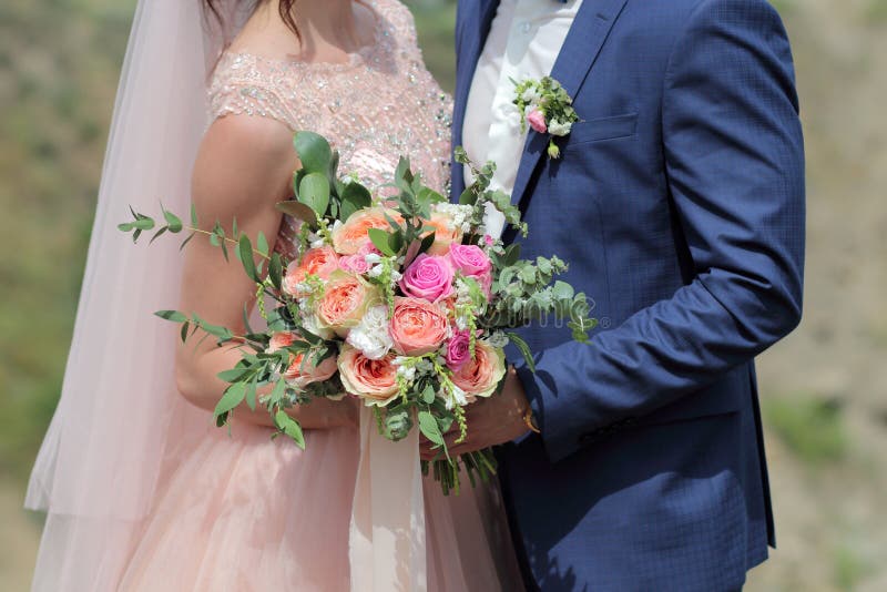 Bride holding a beautiful bridal bouquet. Wedding bouquet of peach roses by David Austin, single-head pink rose aqua, eucalyptus, ruscus, gypsophila. Bride holding a beautiful bridal bouquet. Wedding bouquet of peach roses by David Austin, single-head pink rose aqua, eucalyptus, ruscus, gypsophila.