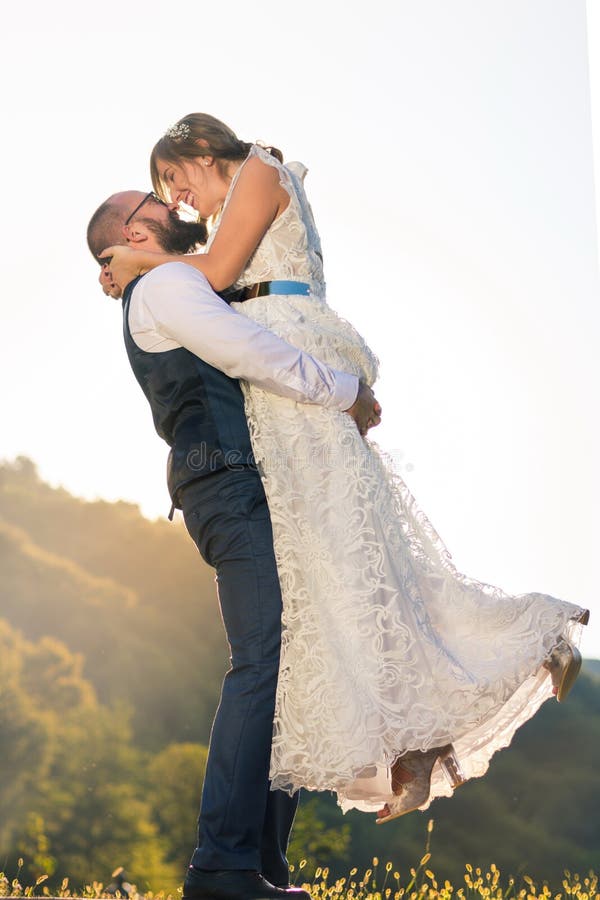Sposa della tenuta dello sposo nel suo armi immagini stock libere da diritti Sposa della tenuta dello sposo nel suo armi immagini stock libere da diritti