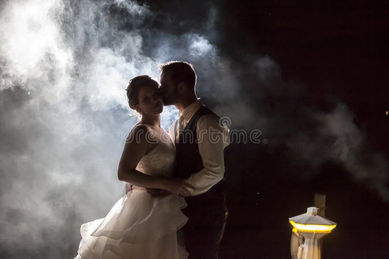 Sposa e sposo che baciano in nebbia alla notte su un bacino fotografia stock Sposa e sposo che baciano in nebbia alla notte su un bacino fotografia stock