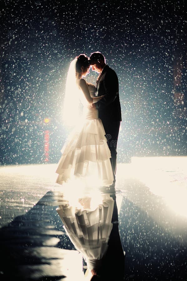 Sposa e sposo che baciano sotto la pioggia fotografia stock libera da diritti Sposa e sposo che baciano sotto la pioggia fotografia stock libera da diritti