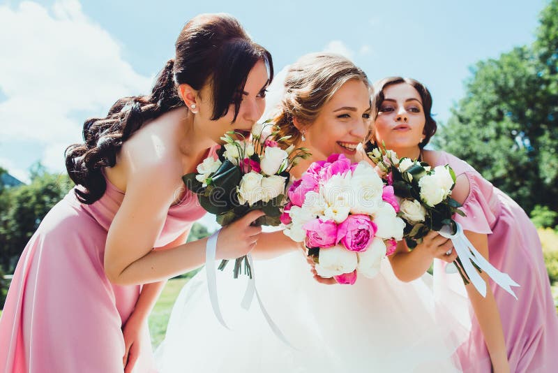 Sposa felice con le damigelle d'onore nel parco sul giorno delle nozze fotografia stock Sposa felice con le damigelle d'onore nel parco sul giorno delle nozze fotografia stock