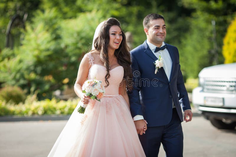 Sposa sorridente con un mazzo e sposo felice che cammina al wedd immagine stock Sposa sorridente con un mazzo e sposo felice che cammina al wedd immagine stock