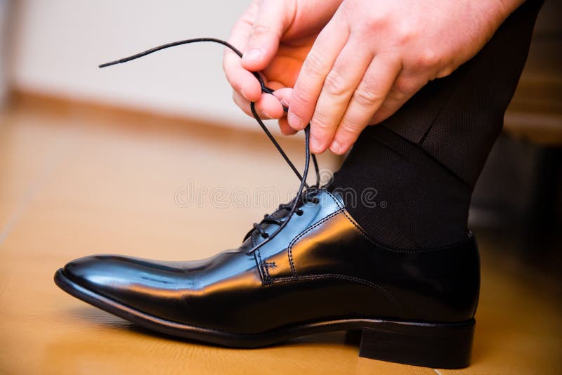 Sposo che mette le sue scarpe di nozze fotografia stock Sposo che mette le sue scarpe di nozze fotografia stock
