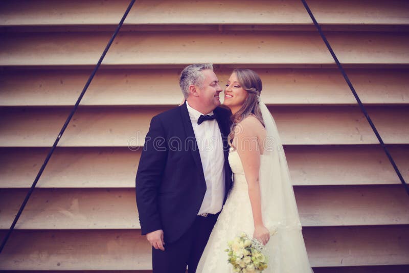 Sposo e sposa vicino ad una parete a strisce fotografie stock libere da diritti Sposo e sposa vicino ad una parete a strisce fotografie stock libere da diritti
