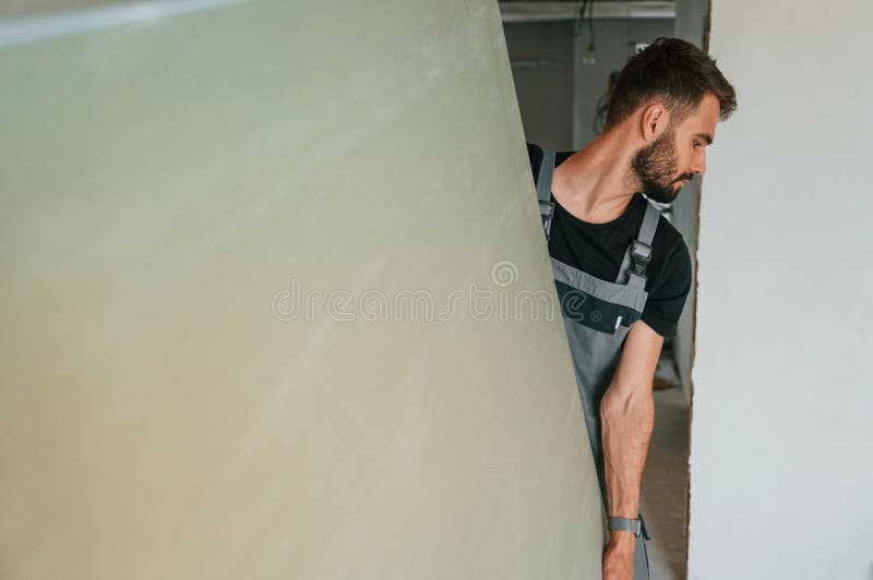 Spostare a mani una parte importante del materiale da costruzione. l'uomo sta riparando nell'appartamento immagine stock libera da diritti