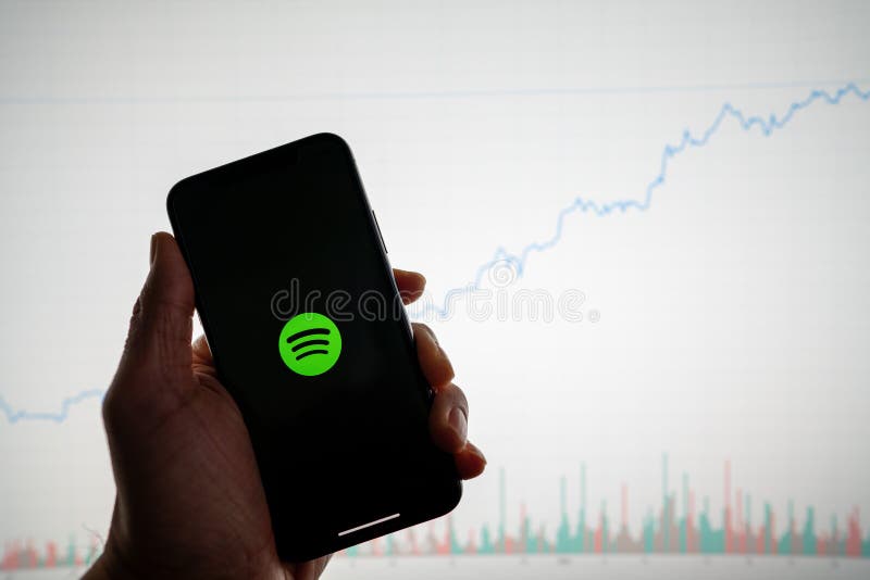 Spotify app on phone with white financial stock chart with price rising upward positive in background