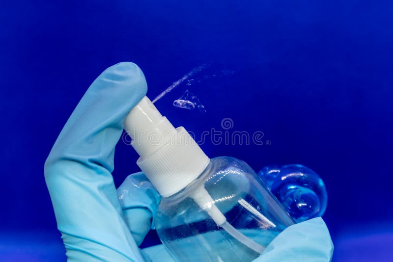 Spray Benutzen Sie Fluid Hand im blauen Handschuh auf Blau