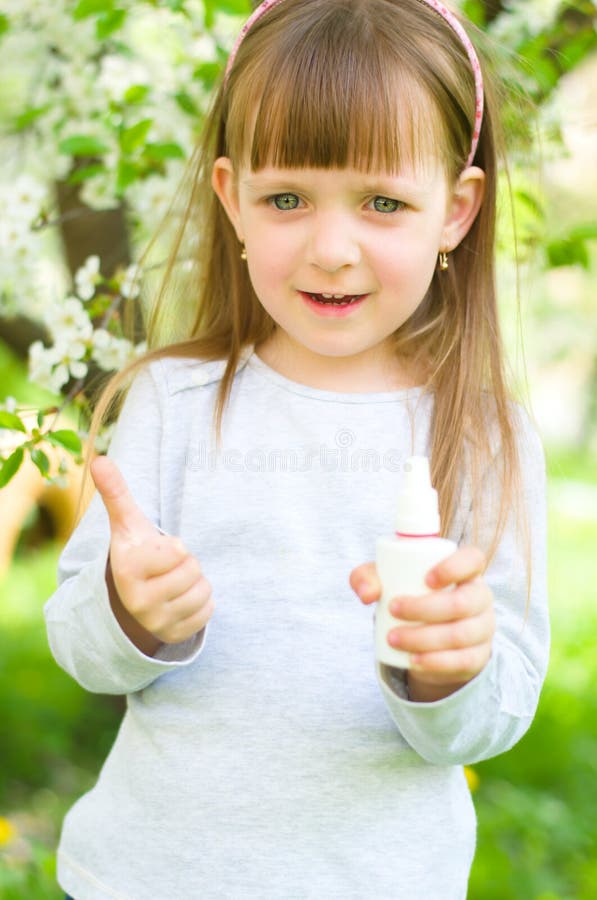 Portrait of a happy girl holding nasal spray,showing thumbs up outdoors. Portrait of a happy girl holding nasal spray,showing thumbs up outdoors