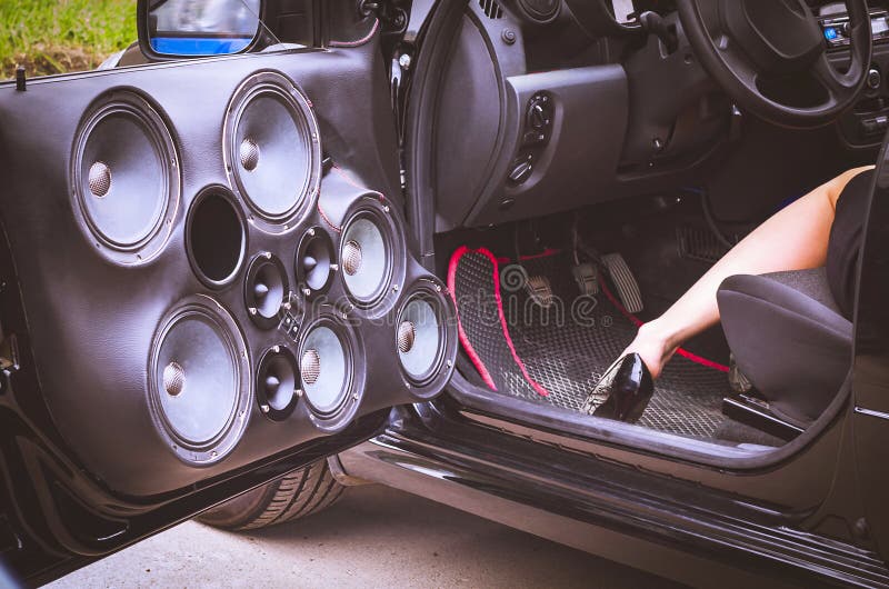 Sprekers van het auto de Audiosysteem in de Geopende Deur met een Vrouw in Hoge Hielen gedeeltelijk Zichtbare Zitting in de Bestu royalty-vrije stock fotografie Sprekers van het auto de Audiosysteem in de Geopende Deur met een Vrouw in Hoge Hielen gedeeltelijk Zichtbare Zitting in de Bestu royalty-vrije stock fotografie