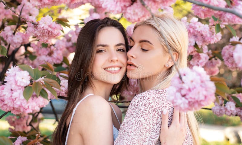 Spring girls. Lesbian couple kissing. Beautiful spring sexy young woman with sakura flowers. Sensual kiss. Lgbt.