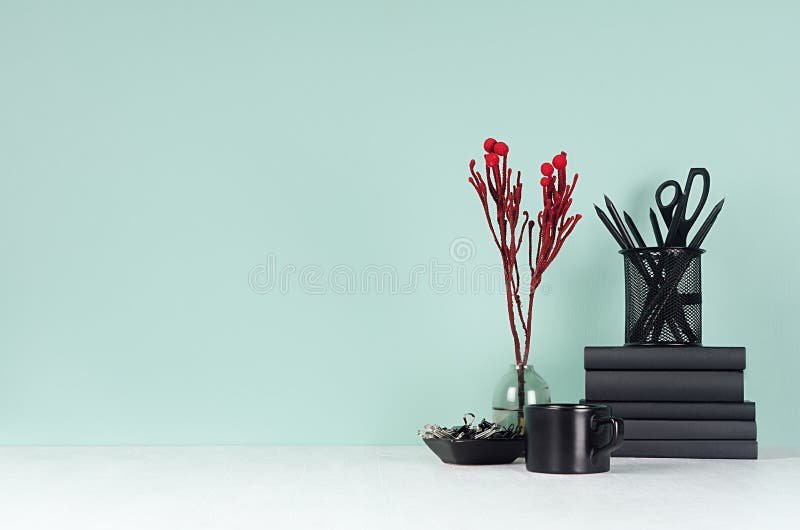 Spring green mint menthe interior of office with black stationery, books, coffee cup and red branch on soft light white wood board