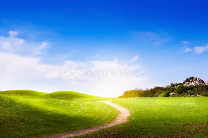 Spring landscape with green grass, road and clouds