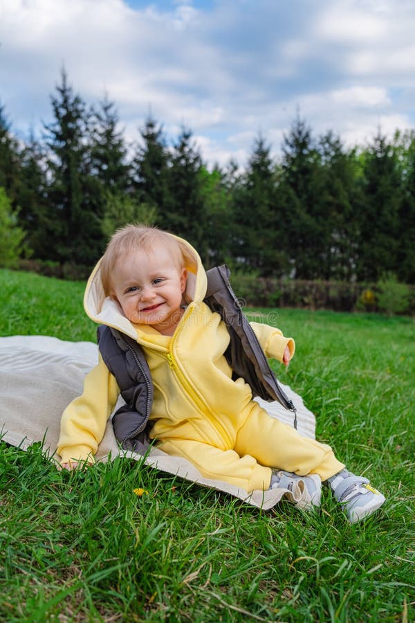 într-un parc de primăvară un băiețel zâmbitor stă pe o pătură pe o pătură stock photos