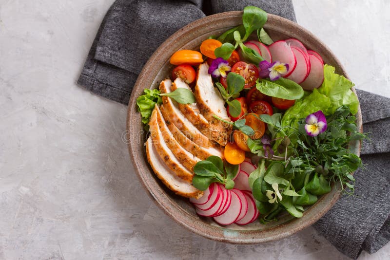 Spring salad with vegetables, chicken breast and edible flowe royalty free stock photography