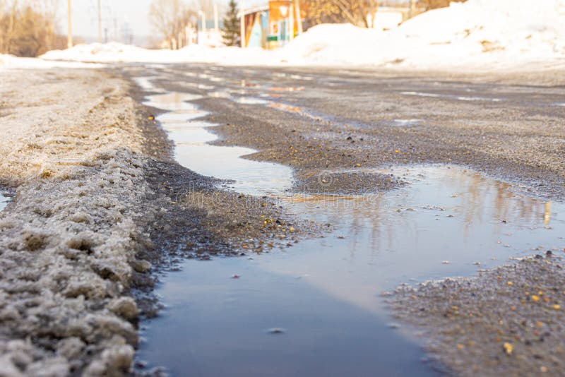 Spring streams flow along the road covered with ice and heavy snow, selective focus royalty free stock photos Spring streams flow along the road covered with ice and heavy snow, selective focus royalty free stock photos
