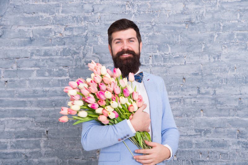 Spring style. Womens day is on march 8. Spring gift. Bearded man hipster with flowers. Love date. international holiday stock photography Spring style. Womens day is on march 8. Spring gift. Bearded man hipster with flowers. Love date. international holiday stock photography