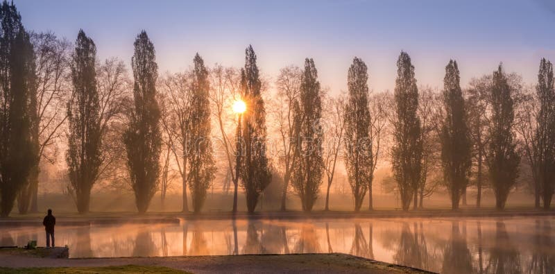 Spring sunrise with trees over water canal with fisherman stock photos