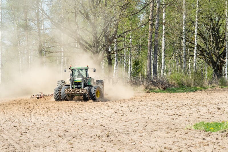Ljusfallshammar, Sweden - May 9, 2016: Tractor pulling a plow during spring in the countryside between Finspång and Ljusfallshammar. Springtime in Sweden is fresh, green and flowering with long bright days. Ljusfallshammar, Sweden - May 9, 2016: Tractor pulling a plow during spring in the countryside between Finspång and Ljusfallshammar. Springtime in Sweden is fresh, green and flowering with long bright days.