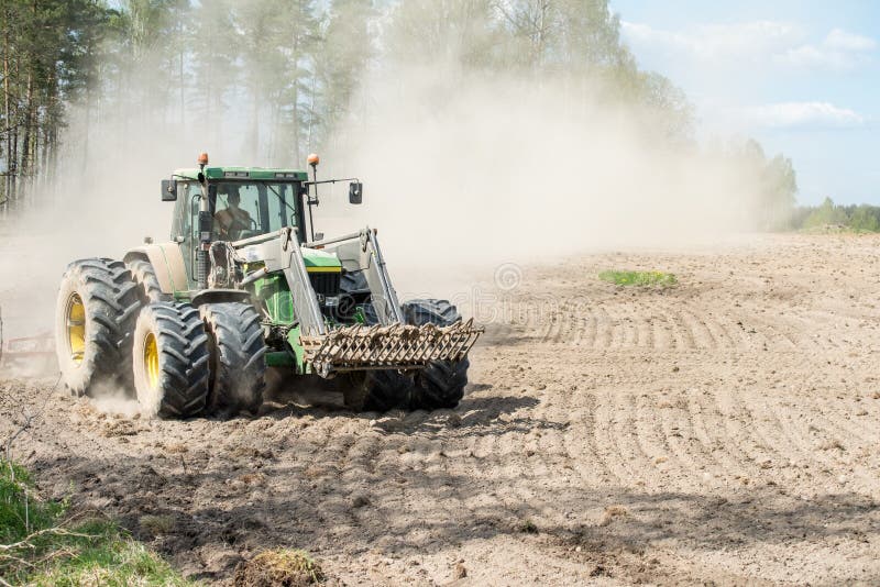 Ljusfallshammar, Sweden - May 9, 2016: Tractor pulling a plow during spring in the countryside between Finspång and Ljusfallshammar. Springtime in Sweden is fresh, green and flowering with long bright days. Ljusfallshammar, Sweden - May 9, 2016: Tractor pulling a plow during spring in the countryside between Finspång and Ljusfallshammar. Springtime in Sweden is fresh, green and flowering with long bright days.