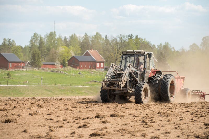 Ljusfallshammar, Sweden - May 9, 2016: Tractor pulling a plow during spring in the countryside between Finspång and Ljusfallshammar. Springtime in Sweden is fresh, green and flowering with long bright days. Ljusfallshammar, Sweden - May 9, 2016: Tractor pulling a plow during spring in the countryside between Finspång and Ljusfallshammar. Springtime in Sweden is fresh, green and flowering with long bright days.