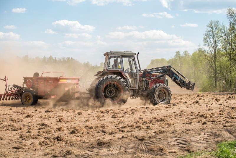 Ljusfallshammar, Sweden - May 9, 2016: Tractor pulling a plow during spring in the countryside between Finspång and Ljusfallshammar. Springtime in Sweden is fresh, green and flowering with long bright days. Ljusfallshammar, Sweden - May 9, 2016: Tractor pulling a plow during spring in the countryside between Finspång and Ljusfallshammar. Springtime in Sweden is fresh, green and flowering with long bright days.