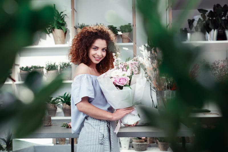 Beaming good-looking curly florist having bright day in workshop royalty free stock photo