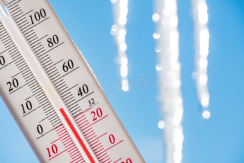 In the spring, the thermometer is on the background of melting icicles and shows a negative temperature.Meteorological conditions