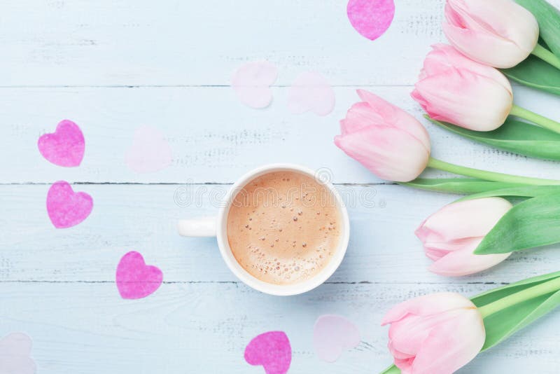Spring tulip flowers and cup of coffee on pastel blue table top view. Beautiful spring breakfast on Mothers or Womans day.Flat lay
