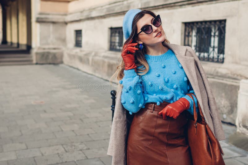 Spring vintage retro fashion female accessories and clothes. Woman wearing blue sweater beret leather skirt sunglasses holding purse on street. Spring vintage retro fashion female accessories and clothes. Woman wearing blue sweater beret leather skirt sunglasses holding purse on street.