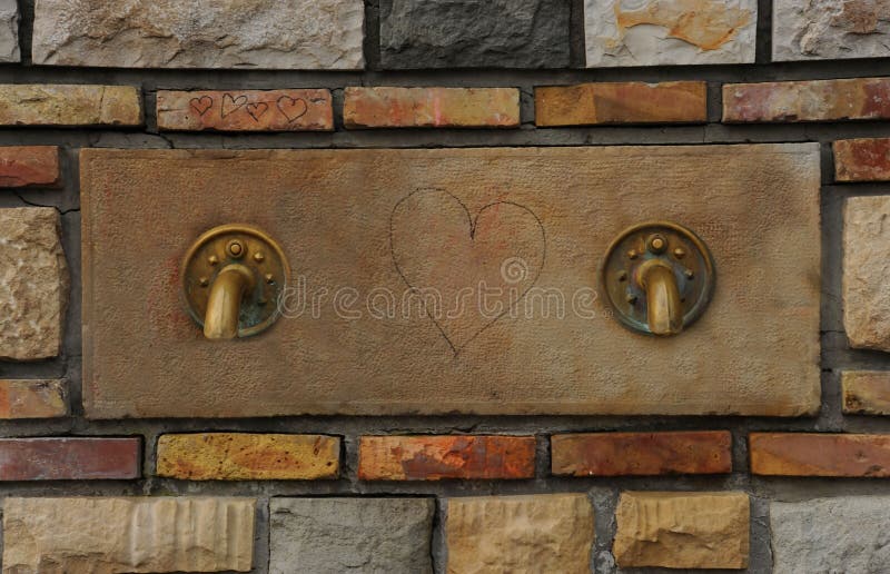 Springbrunnen med de två gamla bronsklappen med hjärtan drunknar in - between