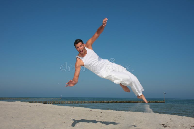 Springender Mann, der hoch auf den Strand fliegt