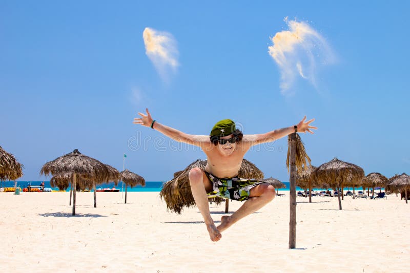 Springt de Appy jonge mens voor vreugde op het strand, tegen blauwe hemel en oceaan royalty-vrije stock foto Springt de Appy jonge mens voor vreugde op het strand, tegen blauwe hemel en oceaan royalty-vrije stock foto