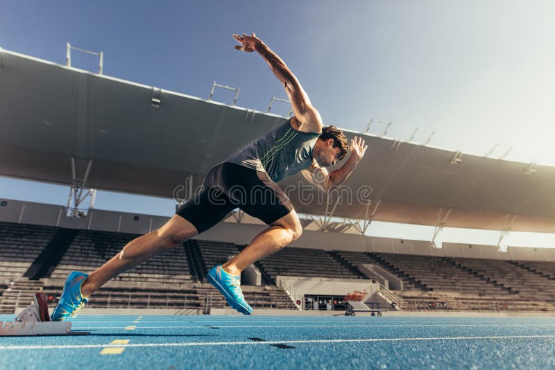 Sprinter che decolla dal blocchetto iniziare sulla pista corrente immagini stock