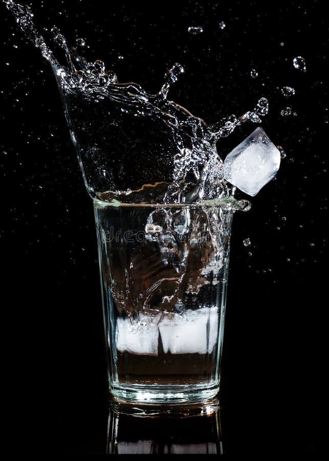 Spritzen des Wassers mit einem Eiswürfel in einem Glas lizenzfreie stockfotos Spritzen des Wassers mit einem Eiswürfel in einem Glas lizenzfreie stockfotos