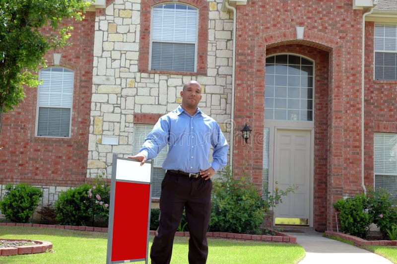 Man stands outside of house for sale, could be buyer, seller, or realtor agent. Sign is blank for your own text. Man stands outside of house for sale, could be buyer, seller, or realtor agent. Sign is blank for your own text.