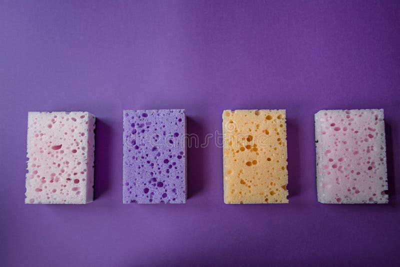 Spugne per i piatti di lavaggio Fondo viola fotografie stock Spugne per i piatti di lavaggio Fondo viola fotografie stock