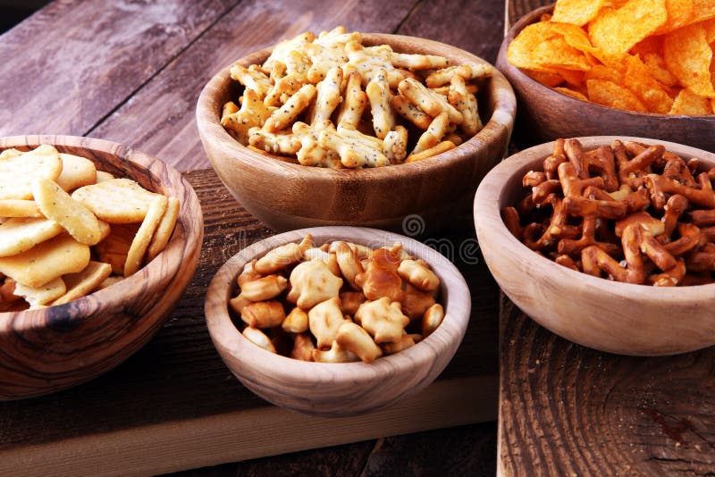 Spuntini salati Ciambelline salate, chip, cracker in ciotole di legno fotografia stock Spuntini salati Ciambelline salate, chip, cracker in ciotole di legno fotografia stock